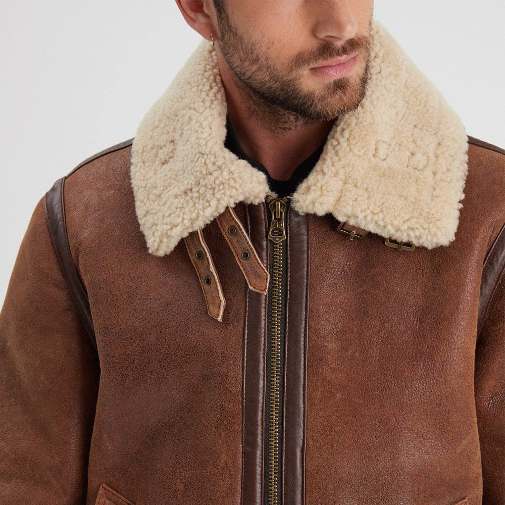 Close-up of cream shearling aviator collar with two leather throat straps, antique buckles, and weathered brown sheepskin