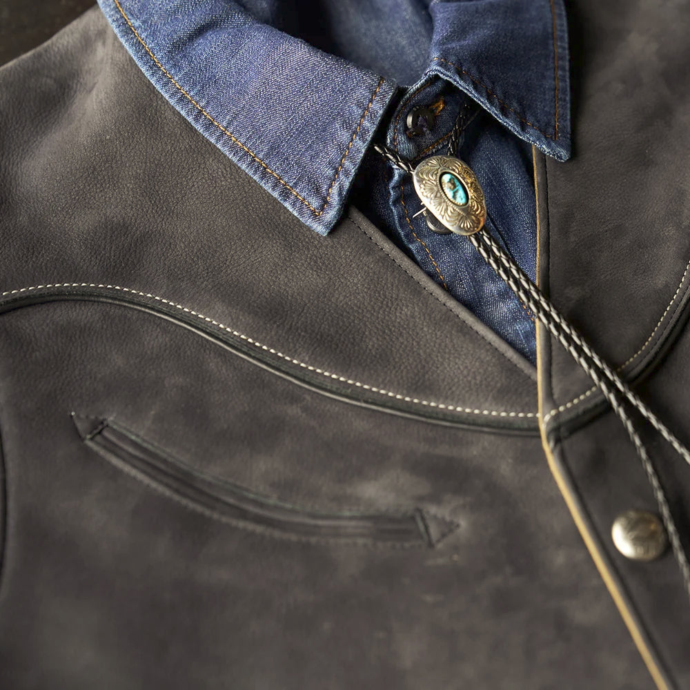 Close-up of a curved double-welt chest pocket, black piping and contrast stitching on the Western nubuck vest