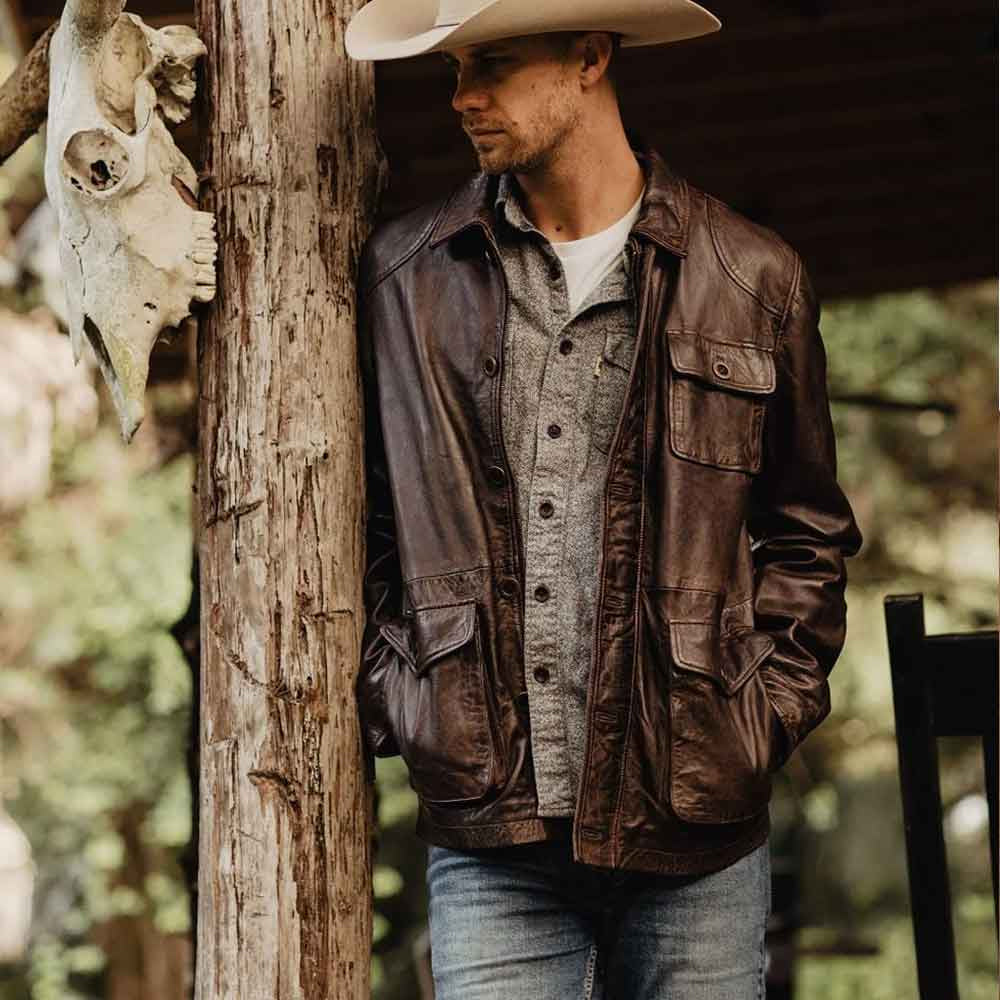 Model wearing men’s dark brown leather utility jacket with relaxed hip-length fit, shirt collar and heritage workwear pockets