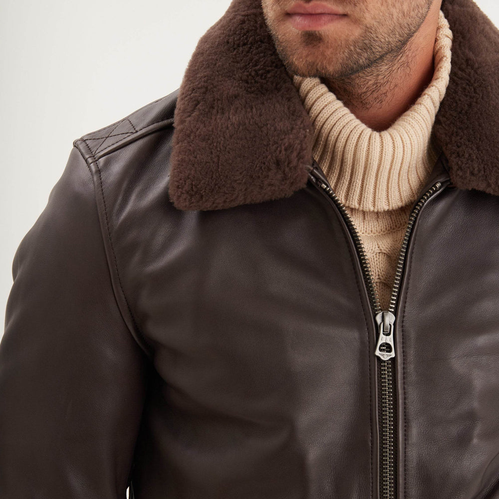 Detailed view of dark-brown removable shearling collar, smooth sheepskin shoulder and metal zipper closure.