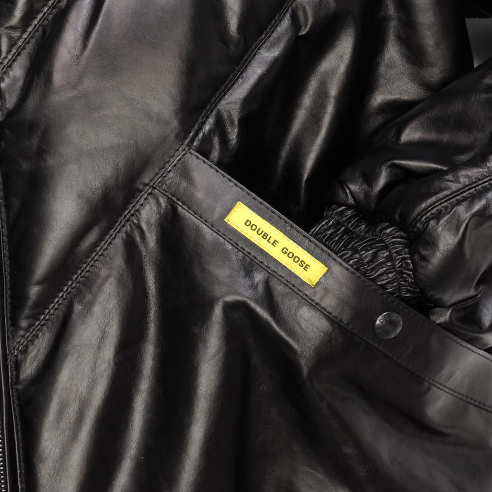 Macro detail of angled handwarmer welt pocket featuring the signature yellow Double Goose woven tag on black lambskin.