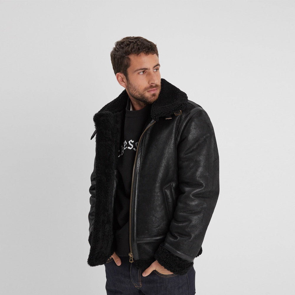 Open men’s black aviator jacket revealing full black shearling lining, angled welt pockets, and a waist-length fit