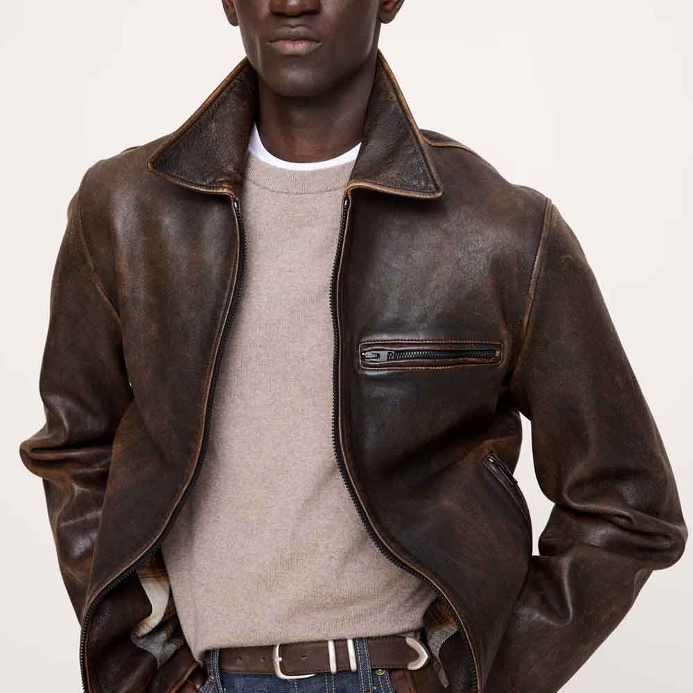 Close model view of full-grain cowhide moto racer jacket featuring broad point collar and horizontal chest zip pocket