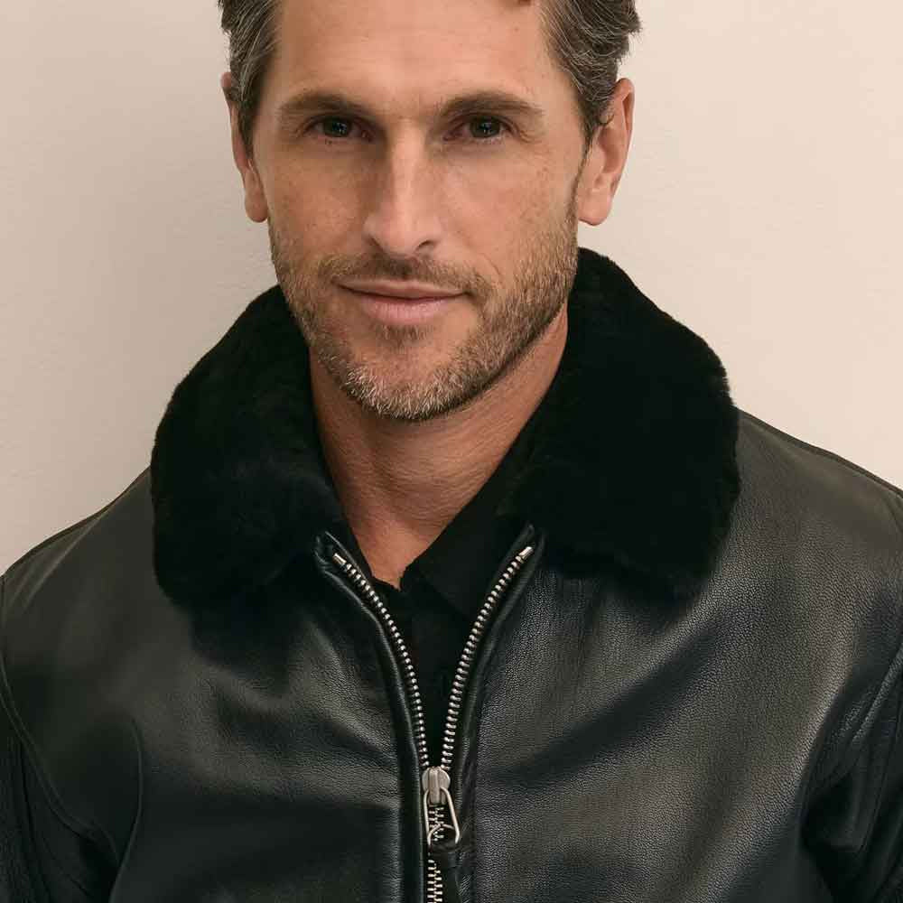 Close view of genuine black shearling flight collar against smooth full-grain black sheepskin leather