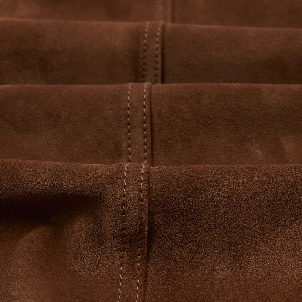 Macro view of genuine tobacco calfskin suede nap with tonal double-row center-seam stitching and natural color movement.