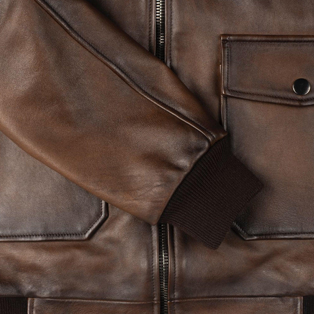 Close-up of gunmetal snap hardware and flap pocket on men's leather jacket sleeve
