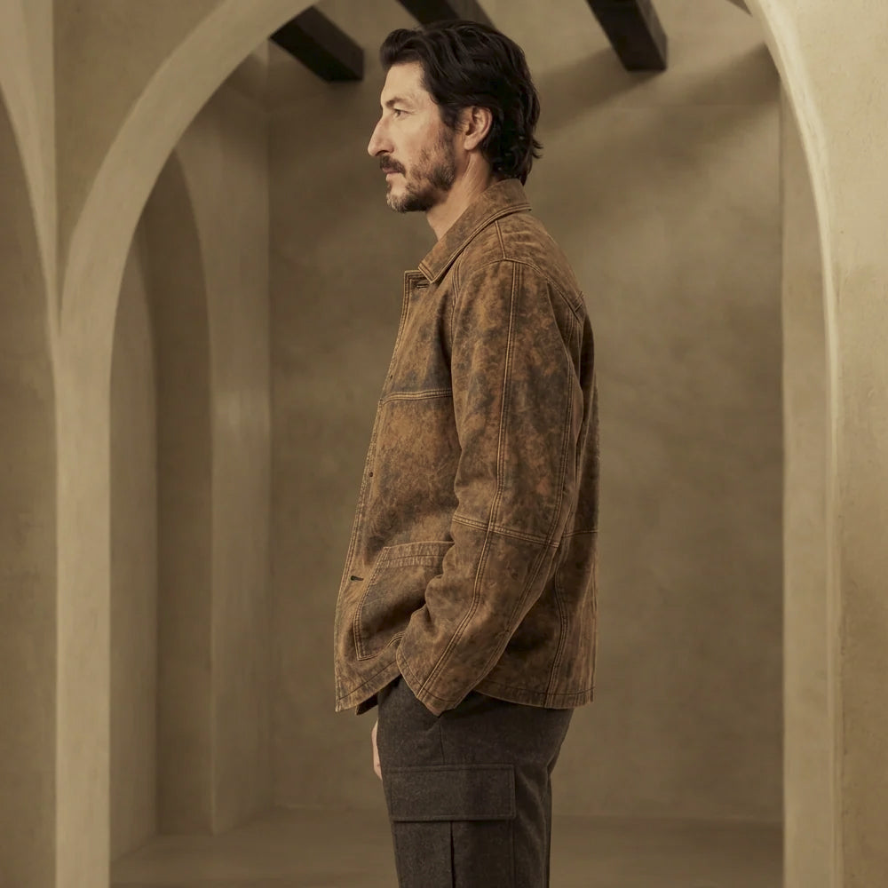 Side profile of hand-waxed leather utility jacket showing segmented sleeves, open cuff and extended hip coverage
