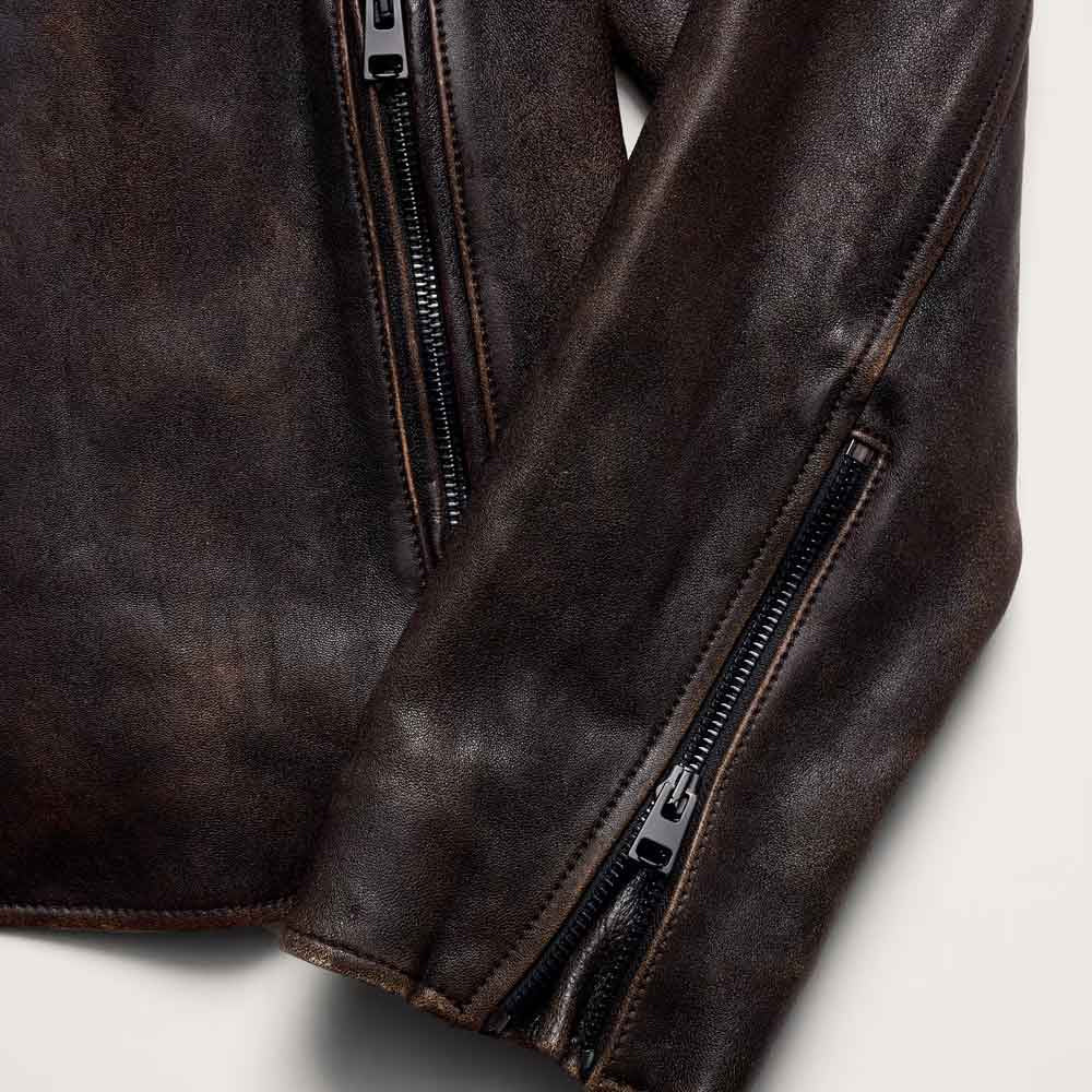 Close-up of leather racing jacket showing angled hand-pocket zipper, adjustable cuff zip and tonal welt stitching
