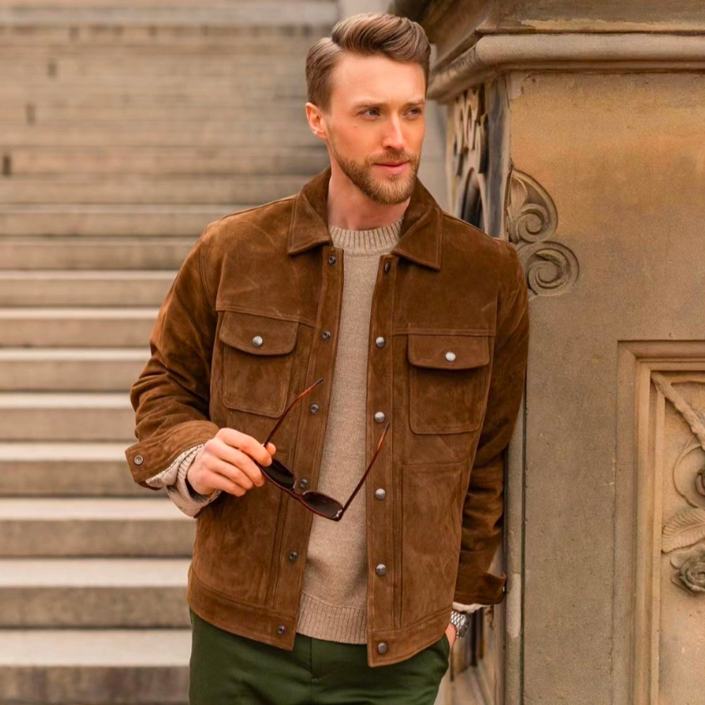 Front view of a blonde male model wearing a premium brown suede leather trucker jacket with snap buttons