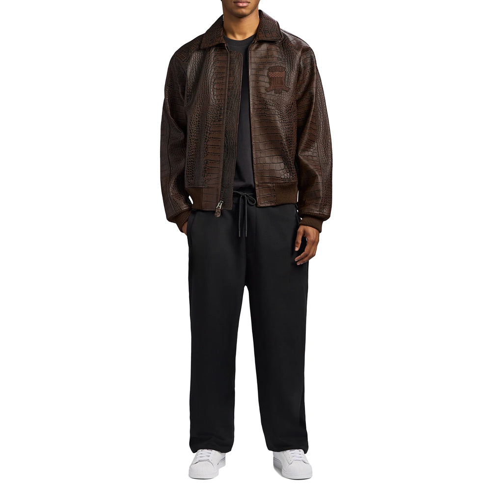 Full-length model styling the brown Avirex croc bomber open over black streetwear and white sneakers