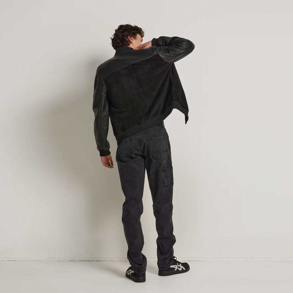 Rear view of men’s black goatskin suede bomber with plain matte back panel, smooth leather yoke and rib-knit hem