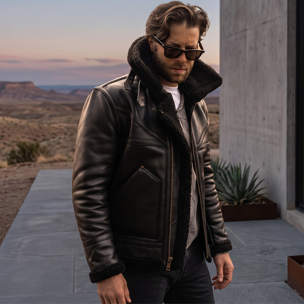 Model wearing men's black grain sheepskin B3 aviator jacket with collar turned up in outdoor landscape