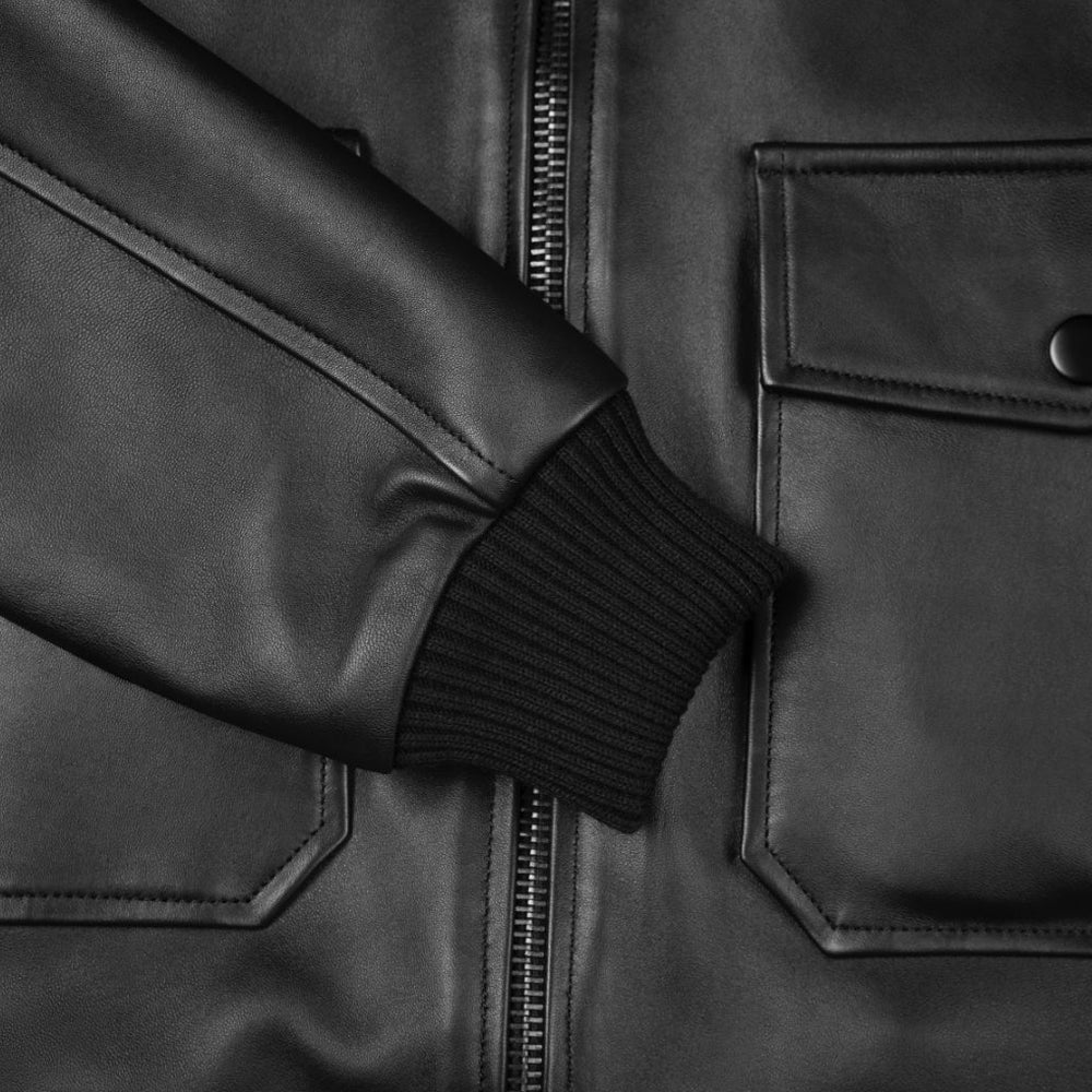 Close-up view of durable black rib-knit cuff and gunmetal zipper on men's leather bomber jacket.