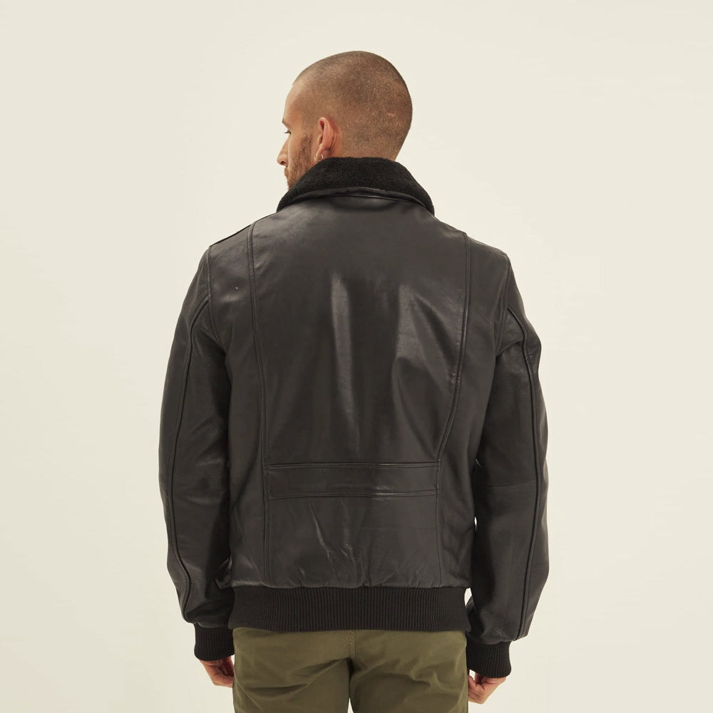 Back view of men's black leather bomber showing vertical shaping seams, lower horizontal panel and ribbed waistband.