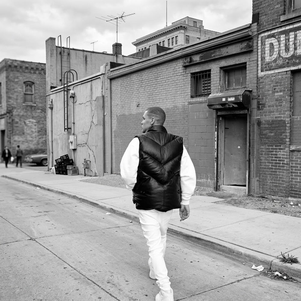 Lifestyle back view of men’s black leather puffer vest showing padded V-chevron panel construction