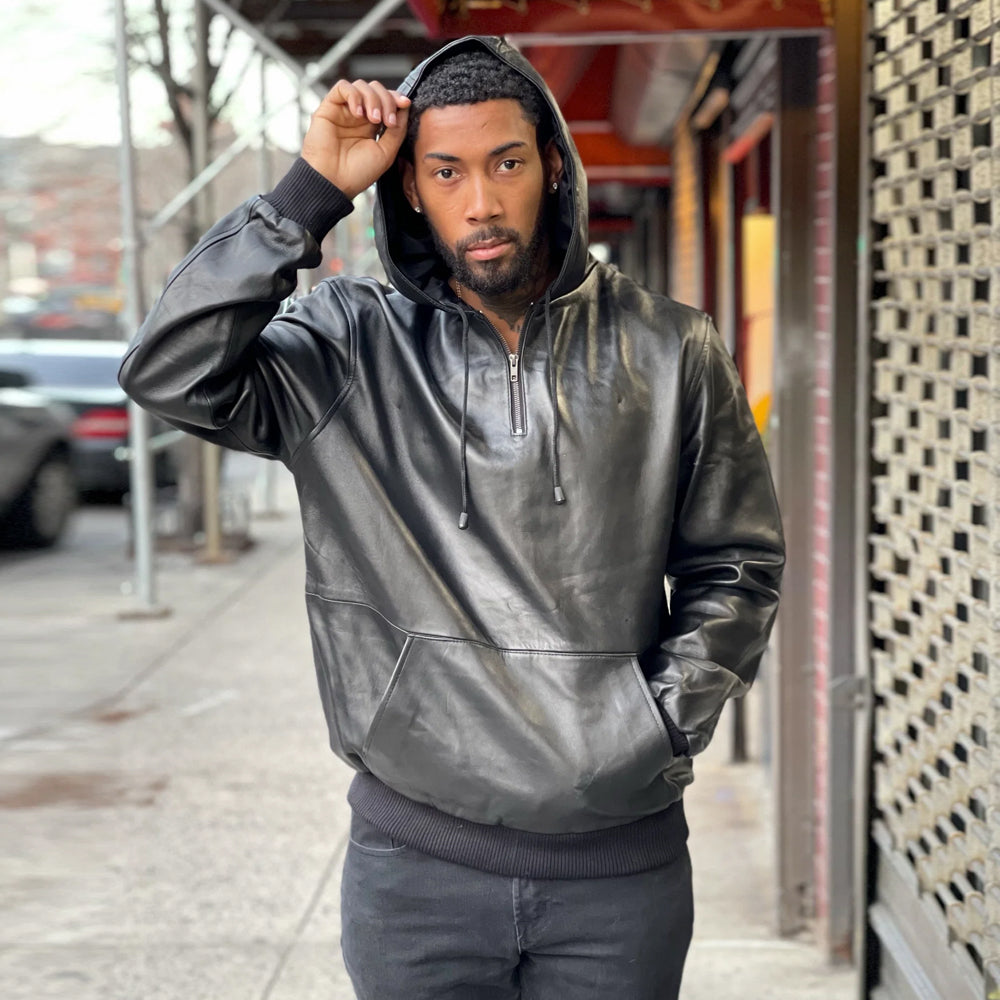 Front view of a model wearing the premium men's black leather pull-over hoodie with the drawstring hood up.