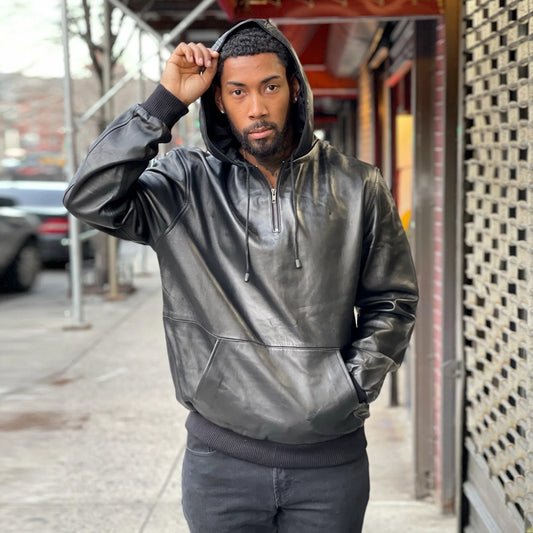 Front view of a model wearing the premium men's black leather pull-over hoodie with the drawstring hood up.