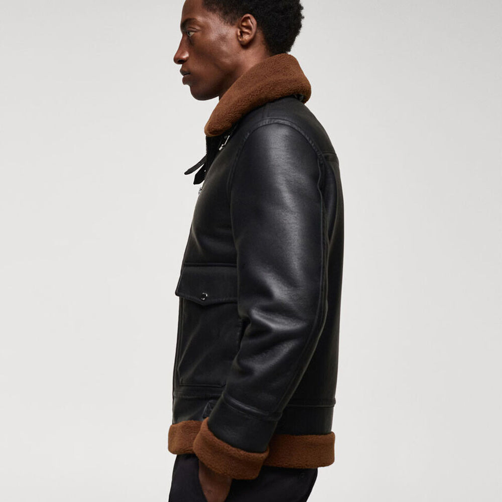 Side profile view of model wearing men's black leather shearling jacket with exposed fur rolled wrist cuffs