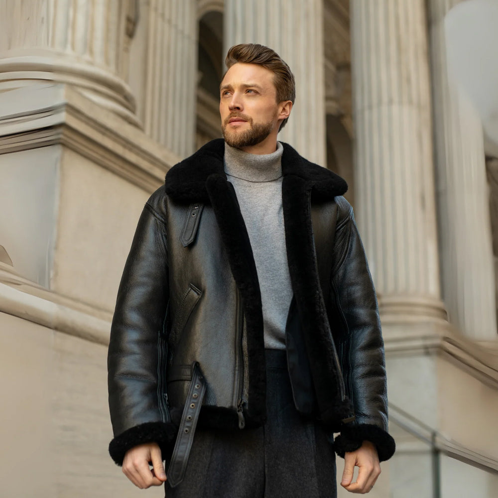Male model wearing a men’s black shearling flight jacket with oversized collar and adjustable leather waist belt
