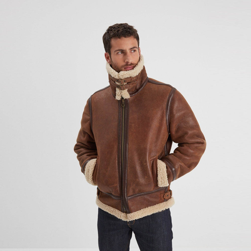 Model wearing men’s distressed brown B-3 shearling jacket with raised cream collar, twin throat buckles, and side waist tabs