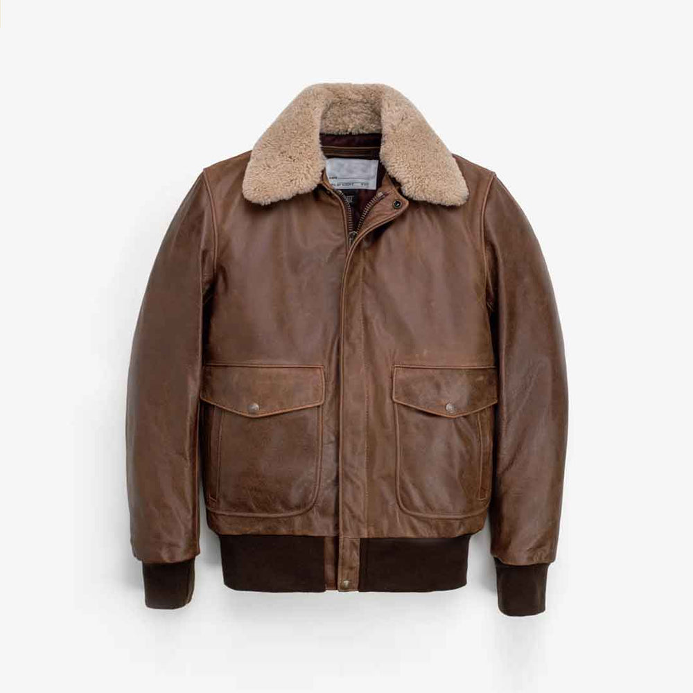 Front flat lay of men’s waxed brown leather bomber with detachable genuine shearling collar and snap-flap pockets