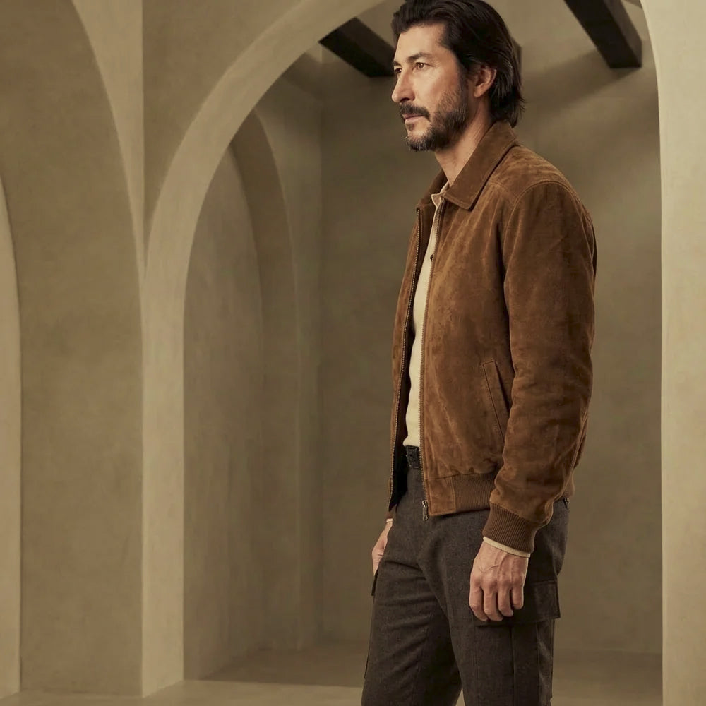 Side profile of men’s brown suede flight jacket highlighting the clean chest, slanted welt pocket and matching knitted cuff.