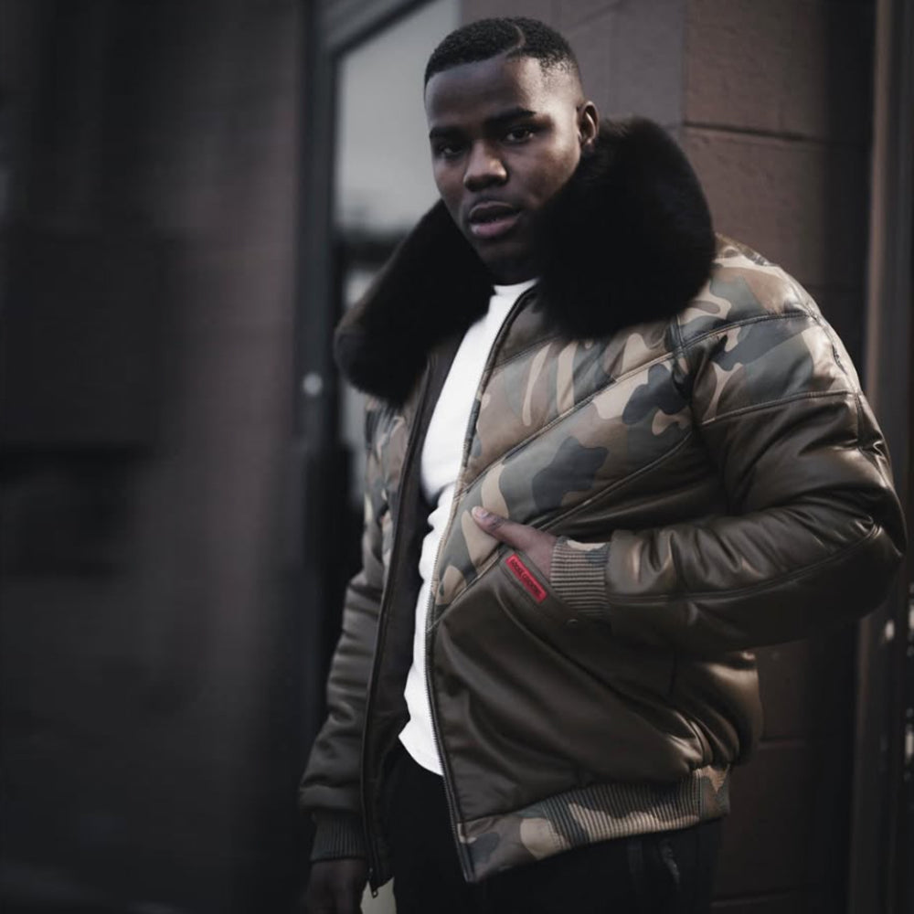 Man wearing camo lambskin puffer jacket with black fox fur collar on city street