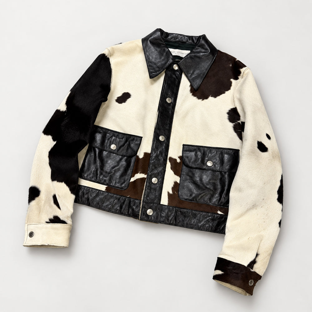 Angled view of men’s cow print leather snap jacket with pointed collar and dark lambskin trim
