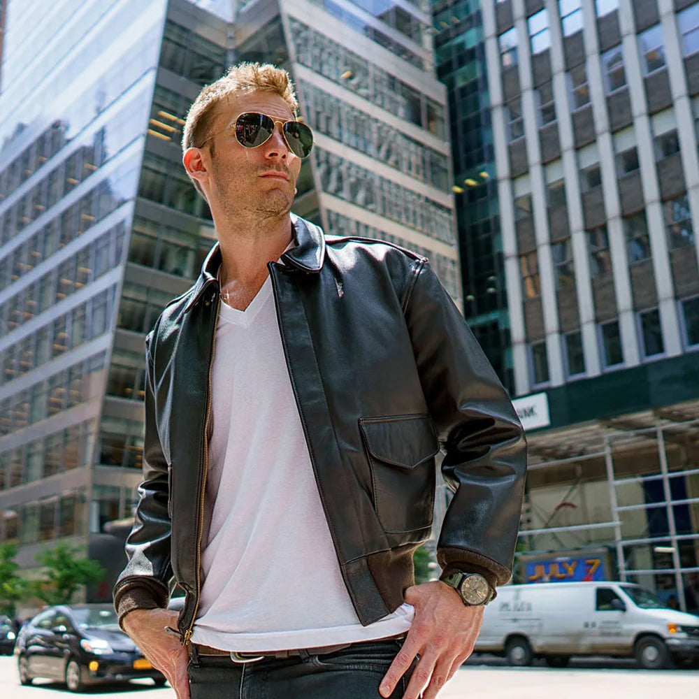 Lifestyle view of model wearing dark brown A-2 goatskin flight jacket with sunglasses in city environment.