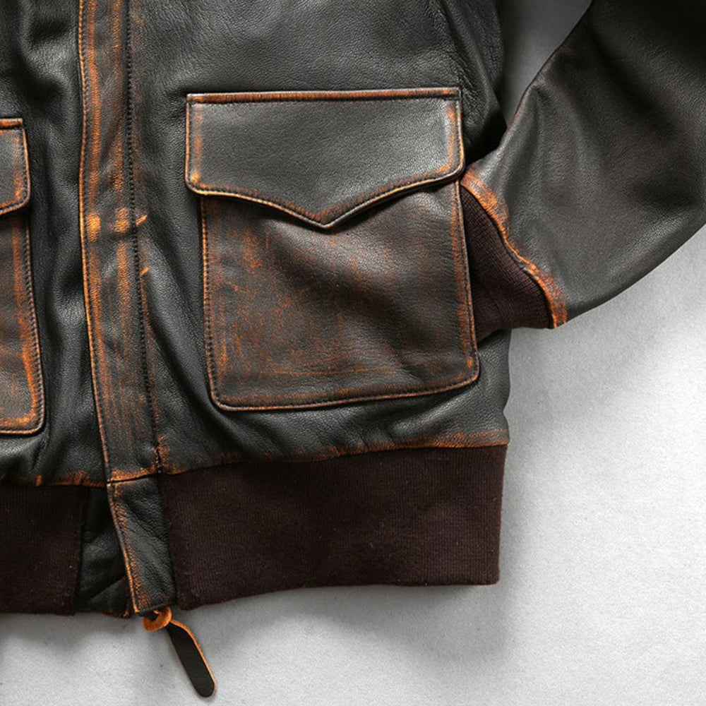 Macro view of hand-distressed tea-core leather front flap cargo pocket with side-entry handwarmer slot.