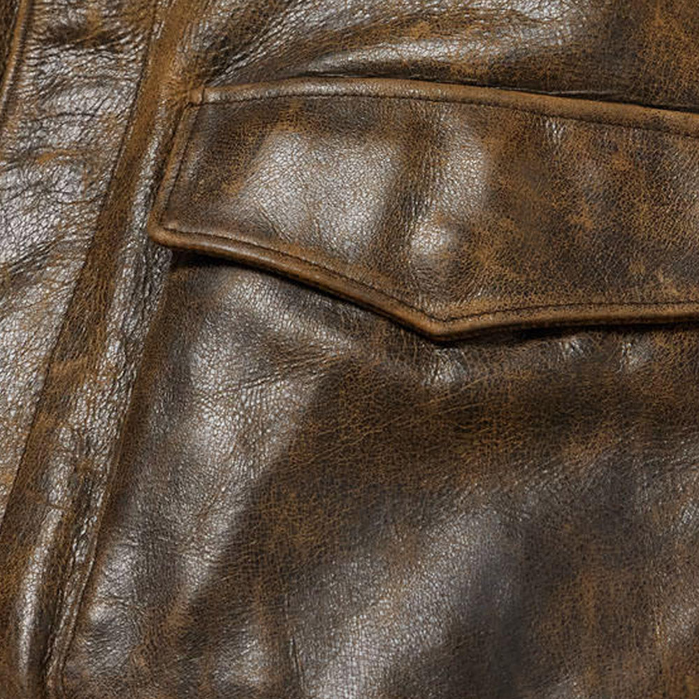 Close-up view of front flap pocket with hidden snap closure on men's vintage leather jacket.