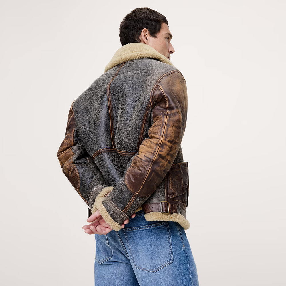 Three-quarter back view of men's distressed sheepskin flight jacket with two-tone sleeves and waist buckles
