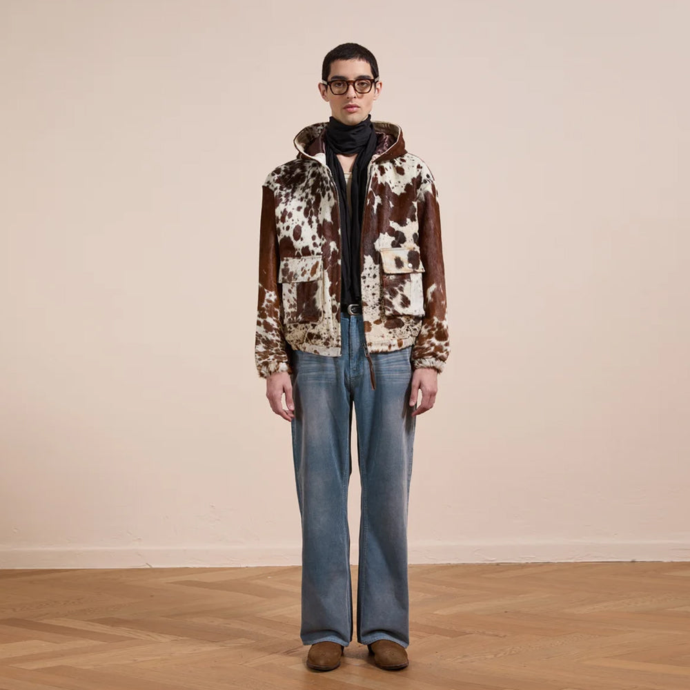Full-length styling view of the men’s hair-on-hide hooded jacket worn with faded jeans and brown Western boots