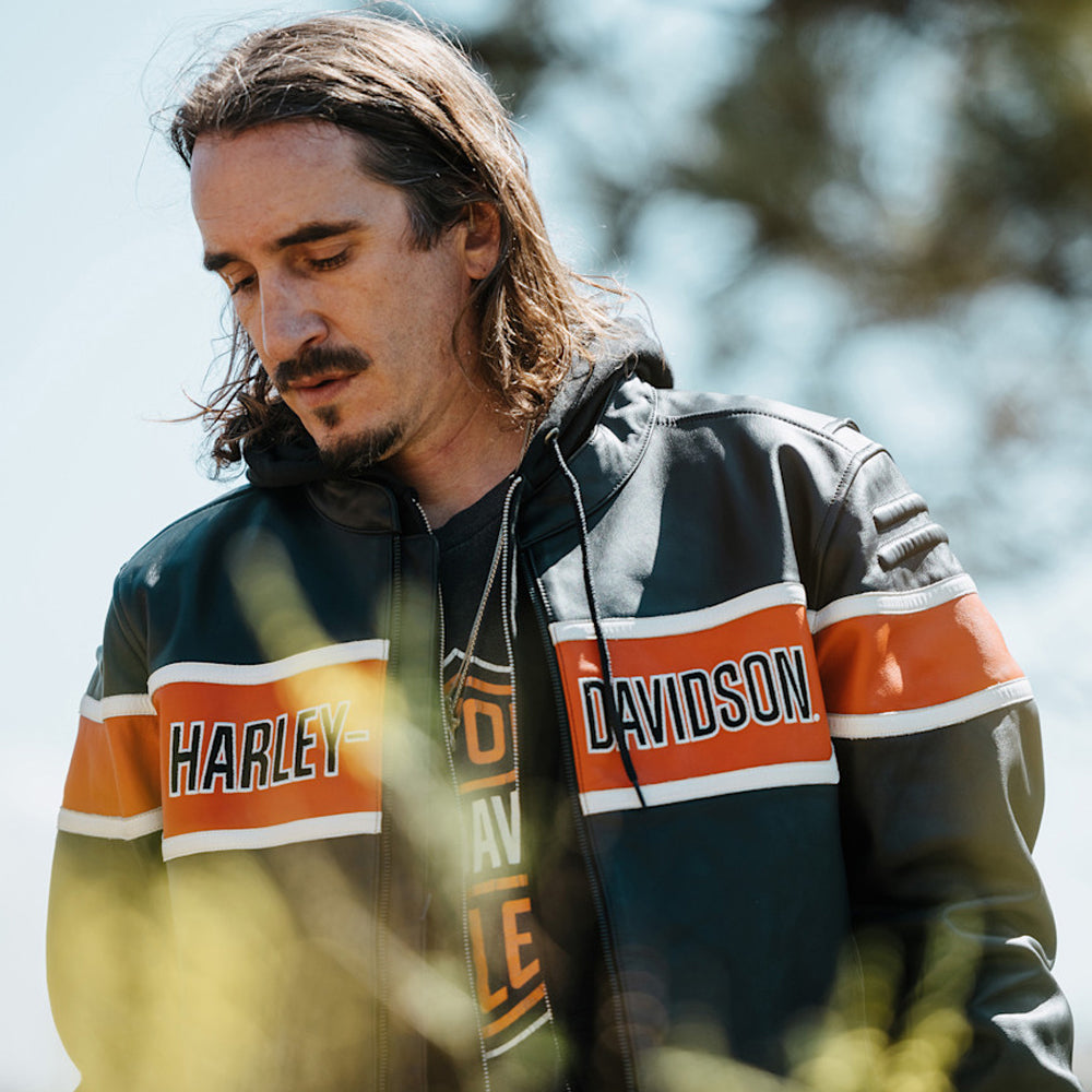 Detailed view of a black Harley-Davidson-style leather biker jacket showing orange panels and embossed shoulders
