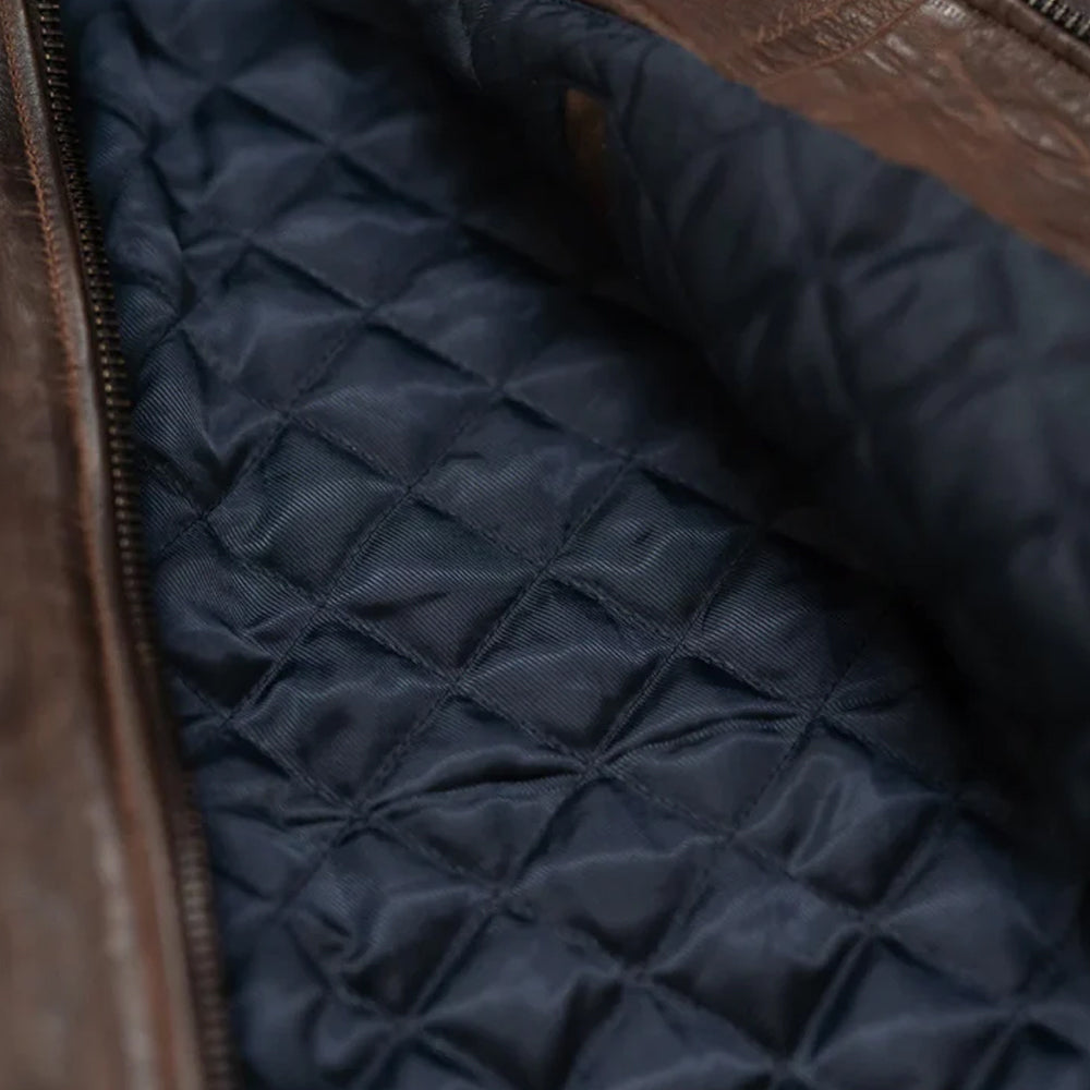 Close-up macro shot of the premium navy blue quilted viscose lining fabric inside a distressed brown leather bomber jacket.