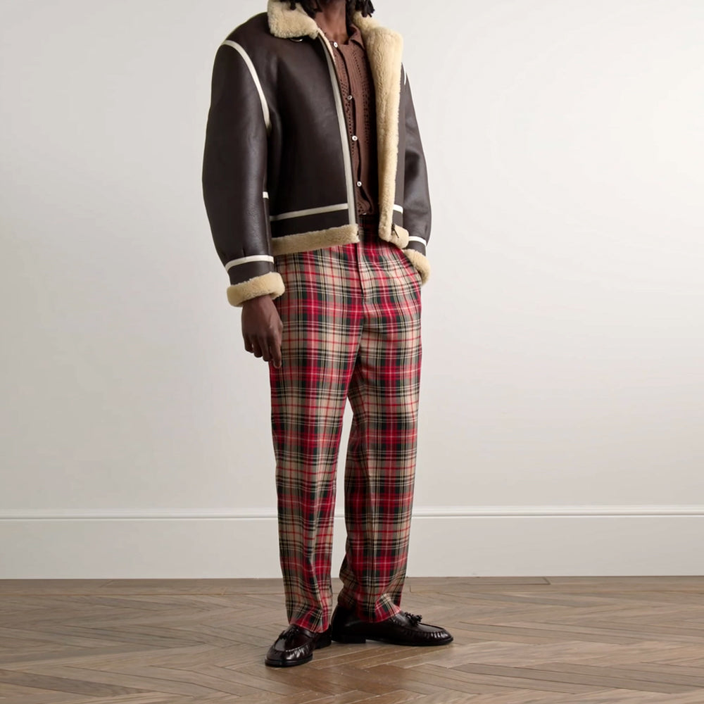 Angled front view of model wearing men's leather-trimmed B3 shearling jacket unzipped over plaid trousers