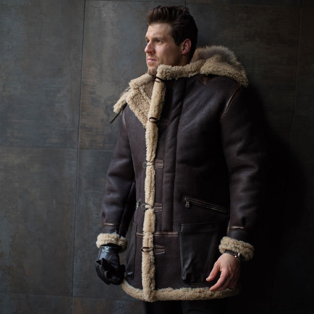 Man wearing men's long RAF B-3 shearling brown leather jacket with real fur hood in an outdoor setting.