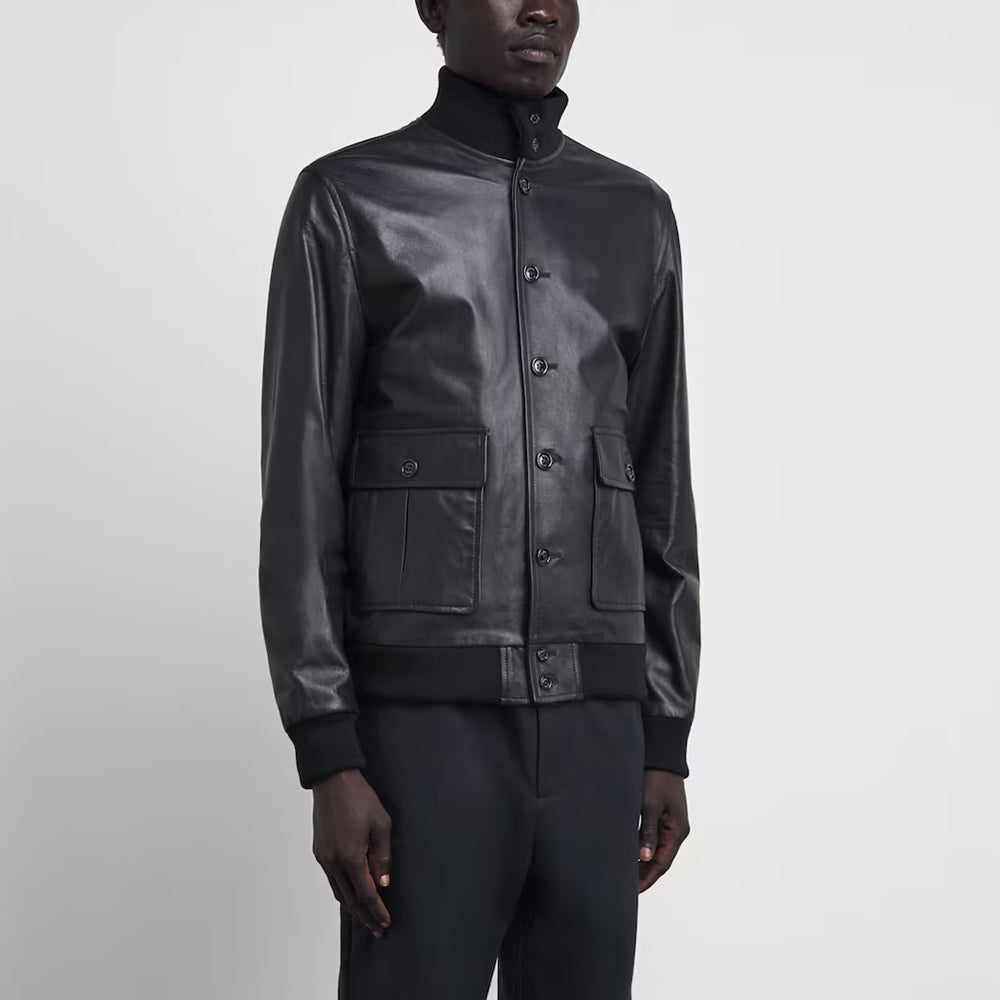Three-quarter view of model wearing men's matte black lambskin Valstar bomber jacket unbuttoned over a sweater.