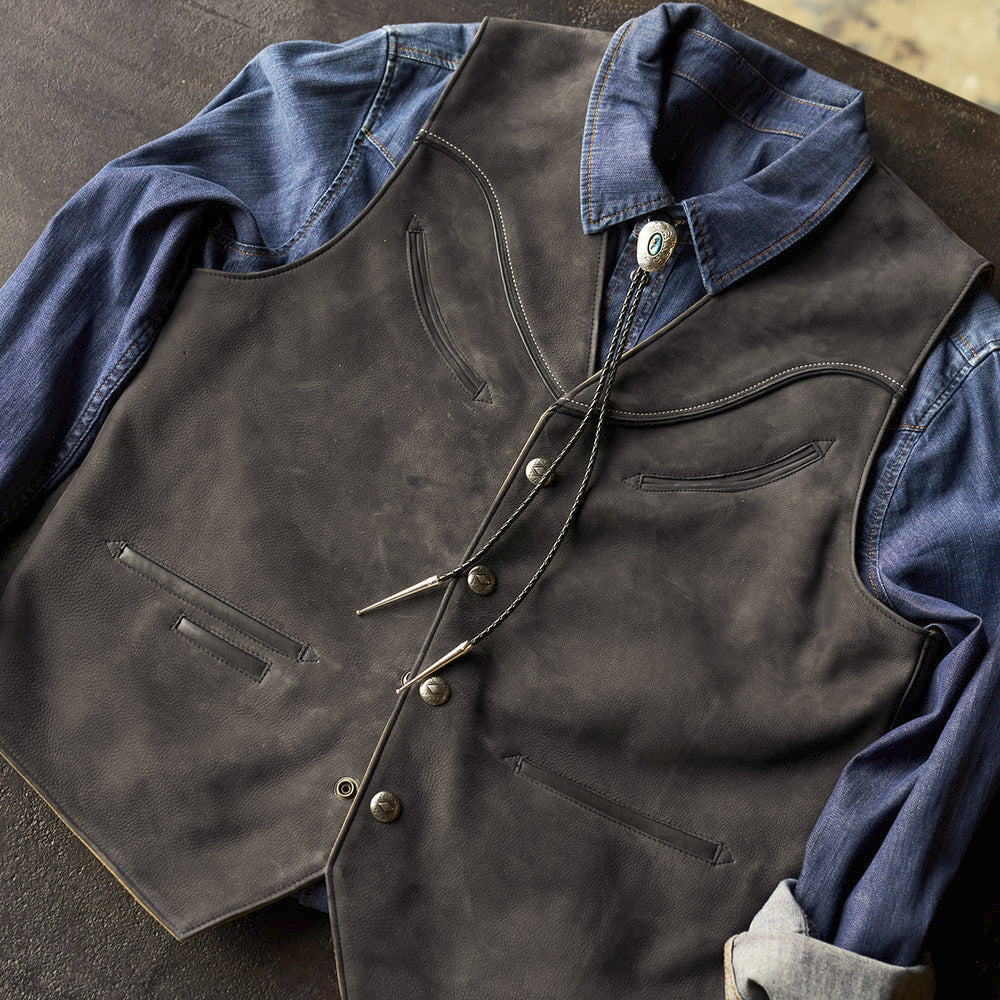 Men’s charcoal nubuck cowboy vest styled over an indigo denim shirt with a Southwestern bolo tie
