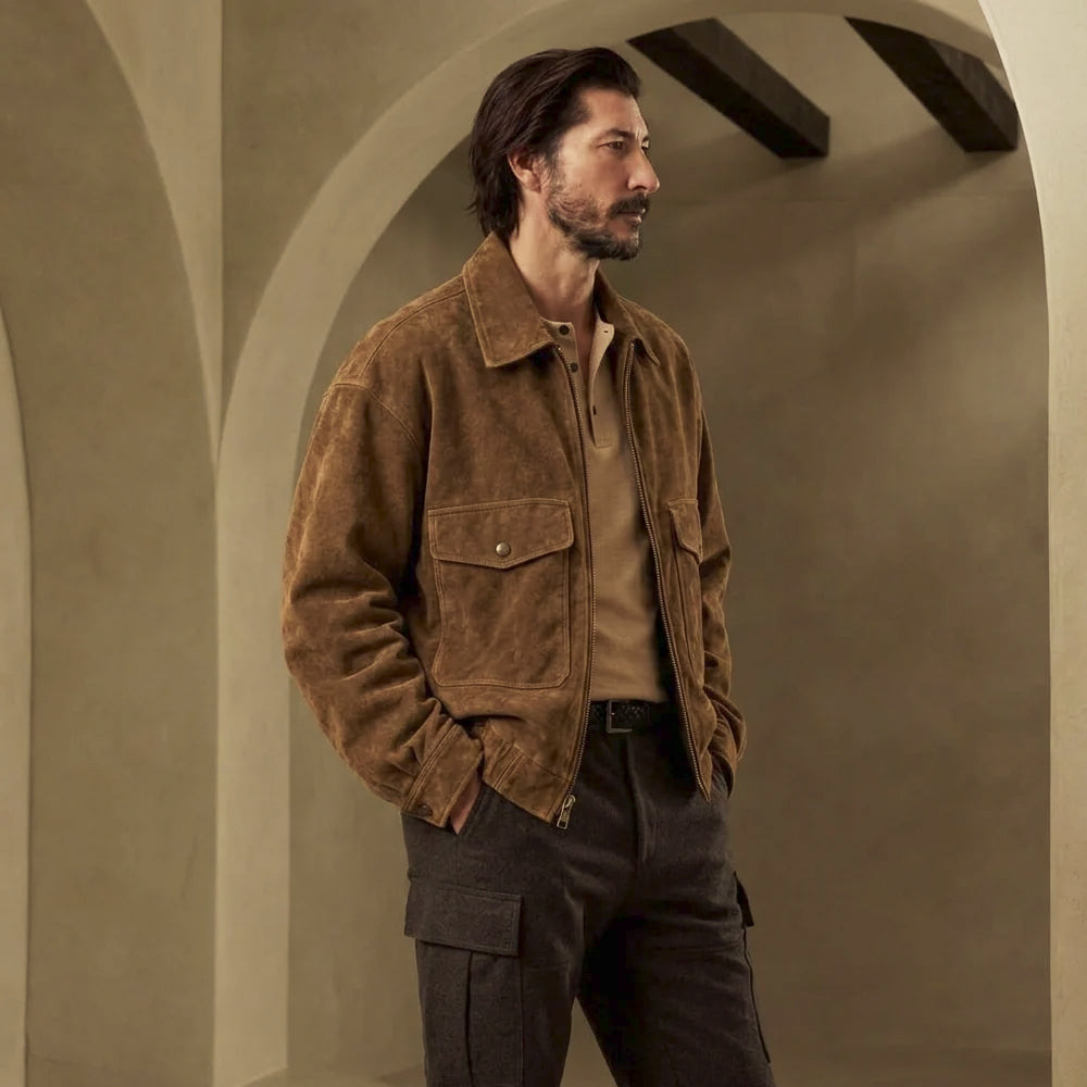 Three-quarter view of men’s oversized brown suede workwear jacket showing dropped shoulders, large chest pockets and roomy sleeves.