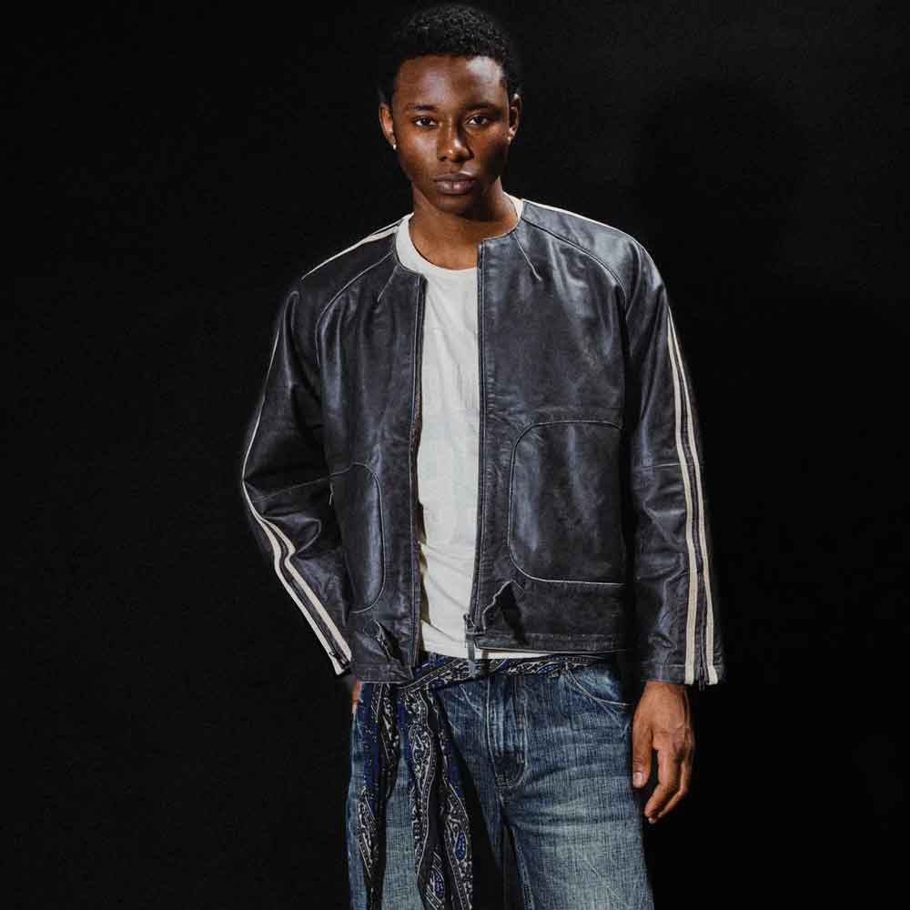 Model wearing men’s retro black leather motorsport jacket open over a white shirt with cream-striped raglan sleeves