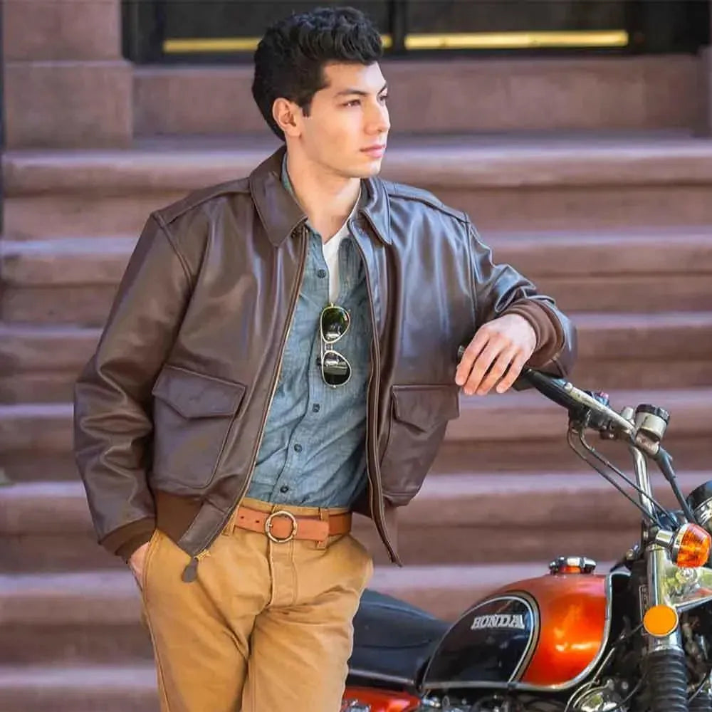 On-model lifestyle view of men's russet horsehide A-2 aviator jacket worn open near vintage motorcycle.