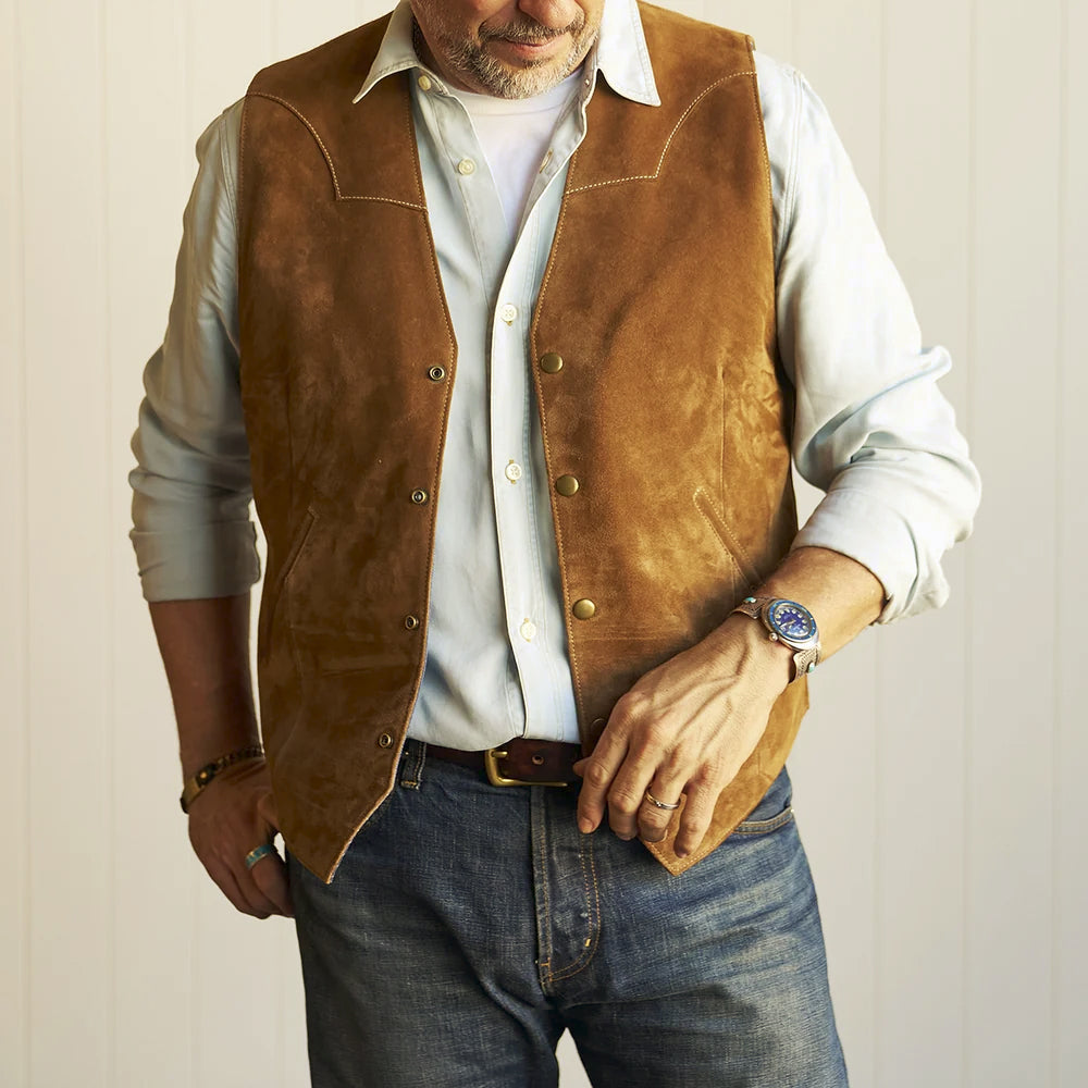 Man wearing the tan Western suede vest open over a pale button-down shirt with blue denim jeans