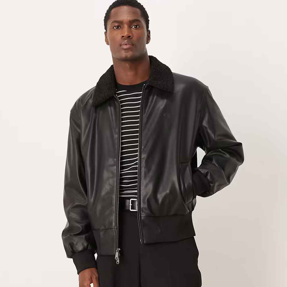Male model wearing waist-length black leather bomber with dual-slider zipper, tonal chest monogram and knitted trim