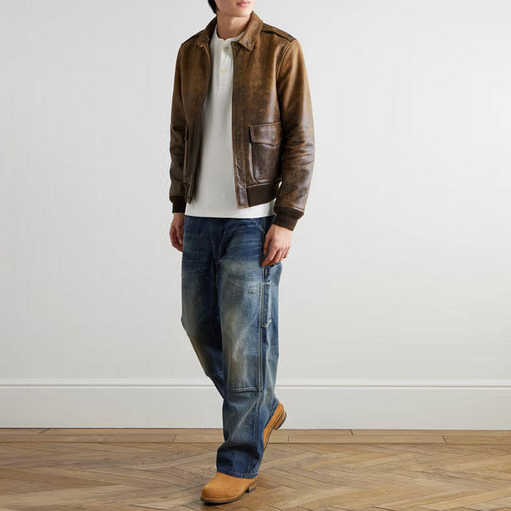 Model wearing men's vintage distressed leather bomber jacket with shoulder straps and rib-knit waistband.