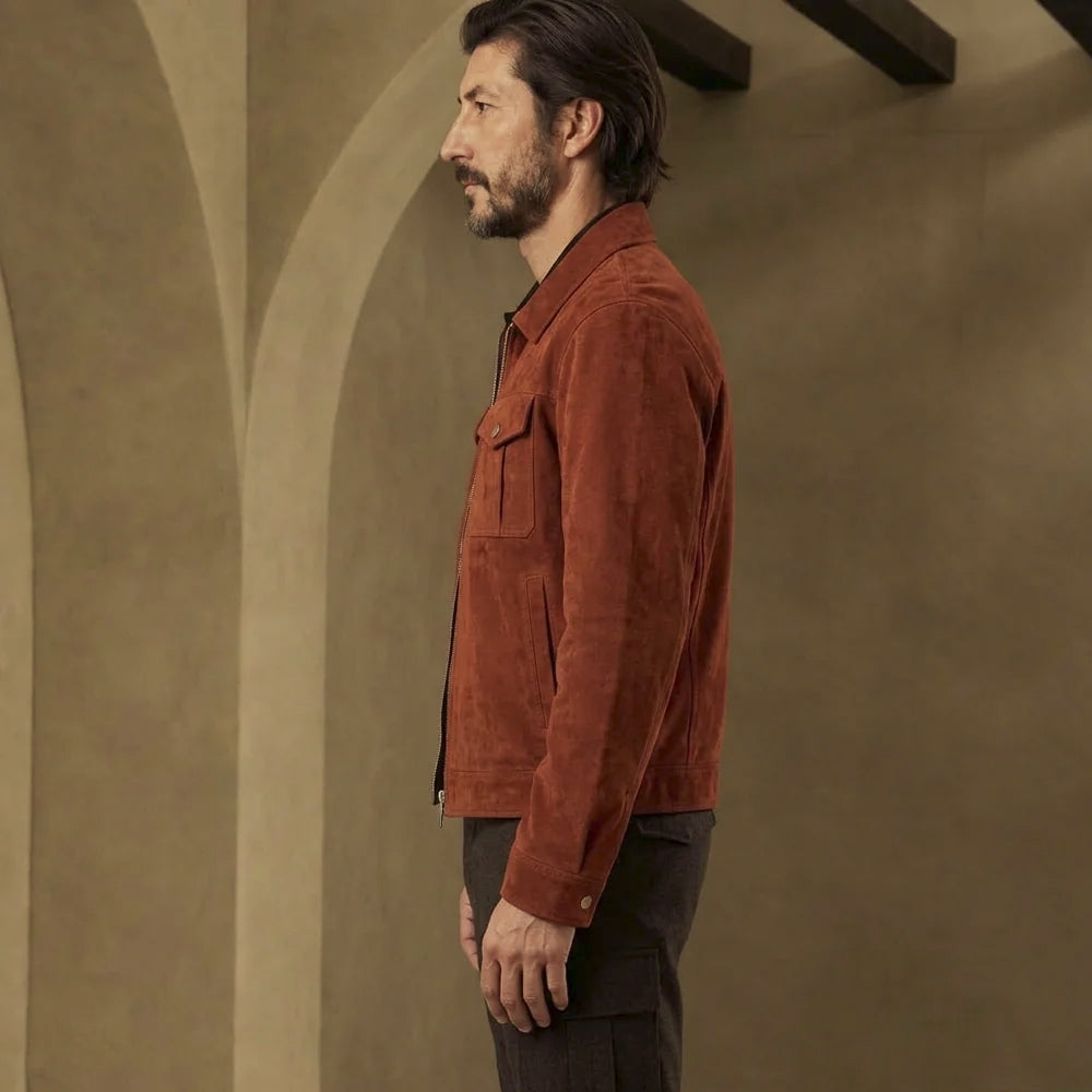 Side profile of men’s waist-length rust suede jacket with clean shirt collar, lower welt pocket and button-fastened straight cuff.