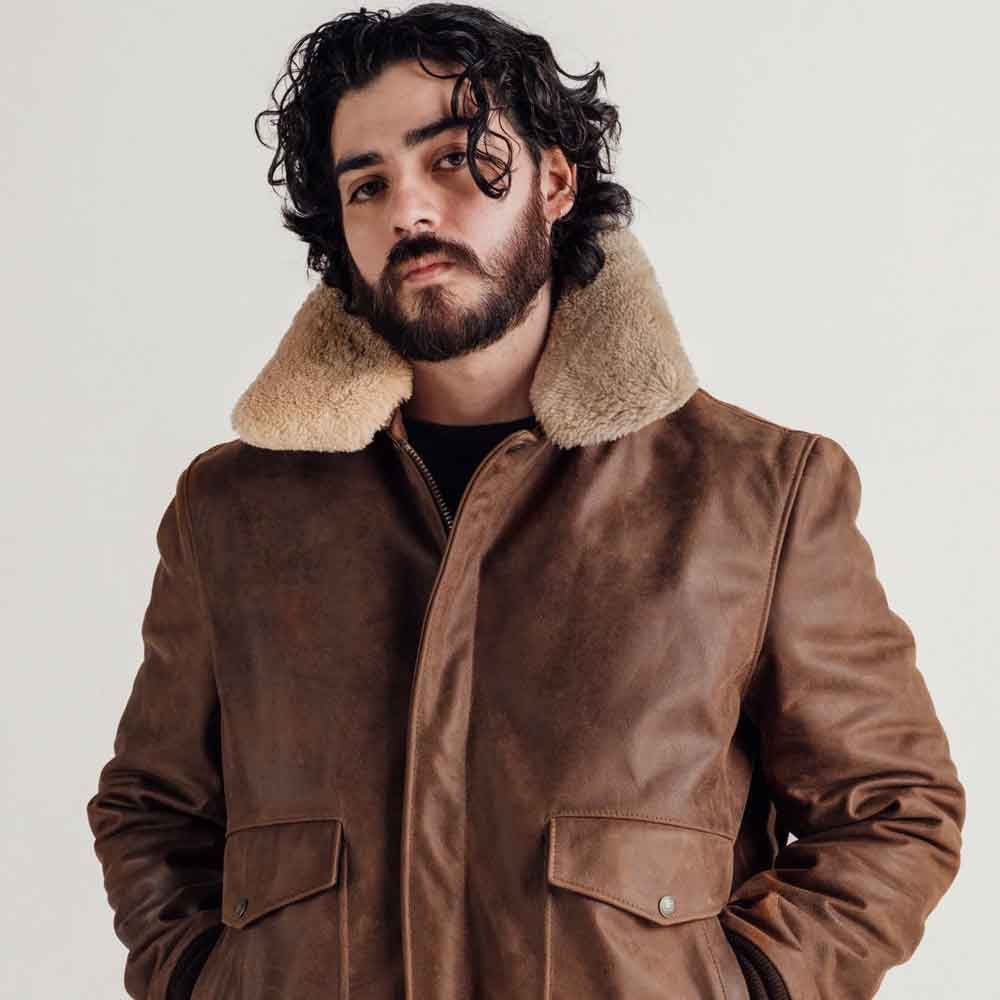 Male model wearing brown waxed sheepskin bomber with raised detachable genuine shearling collar and antique zipper