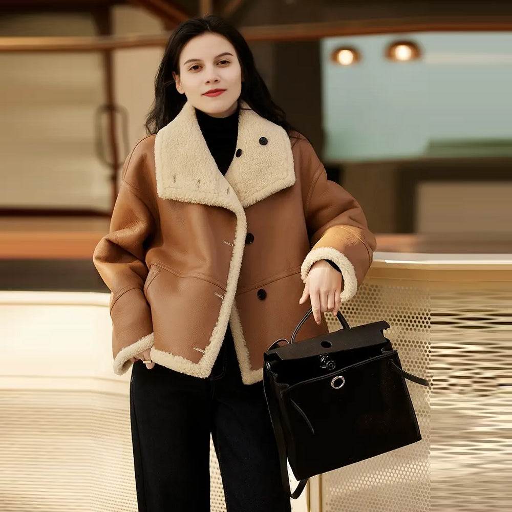 Full-length view of a woman standing and wearing the oversized brown sheepskin shearling winter jacket.