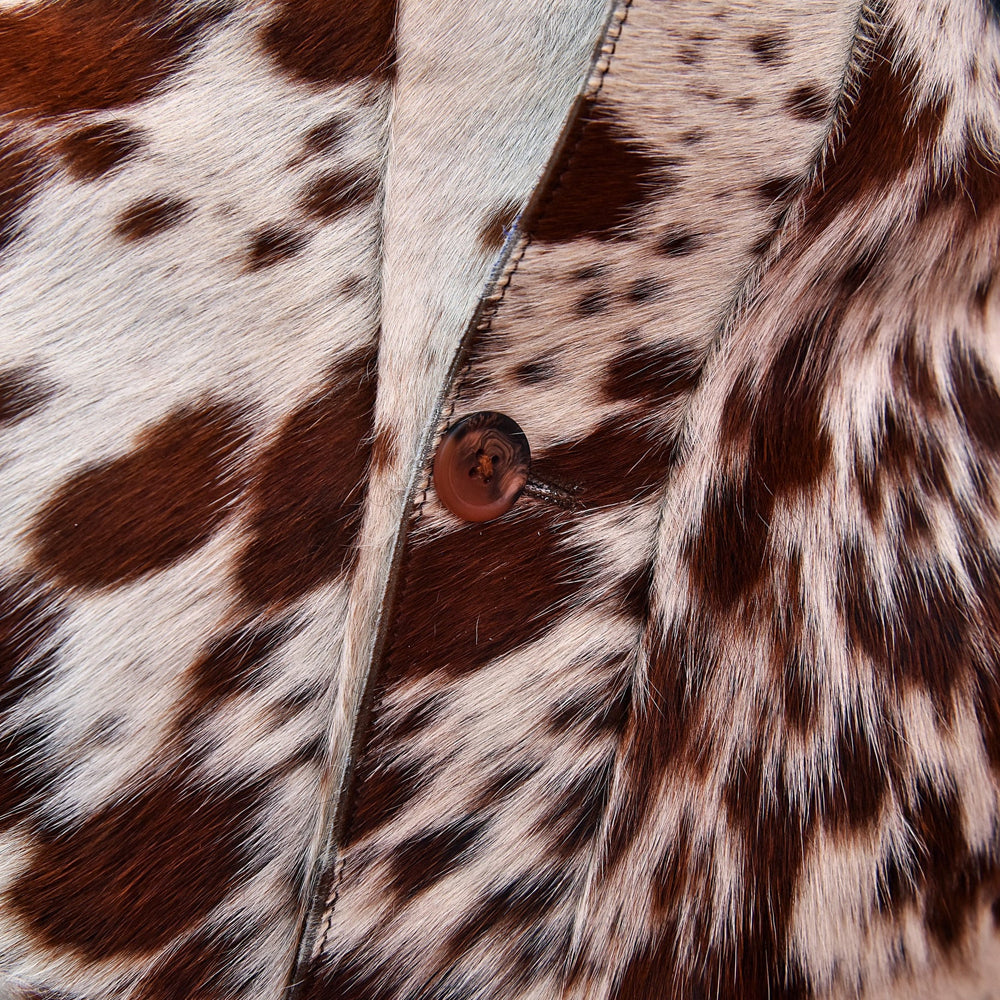 Detailed view of the button placket, topstitching and natural brown-and-ivory cowhide hair texture