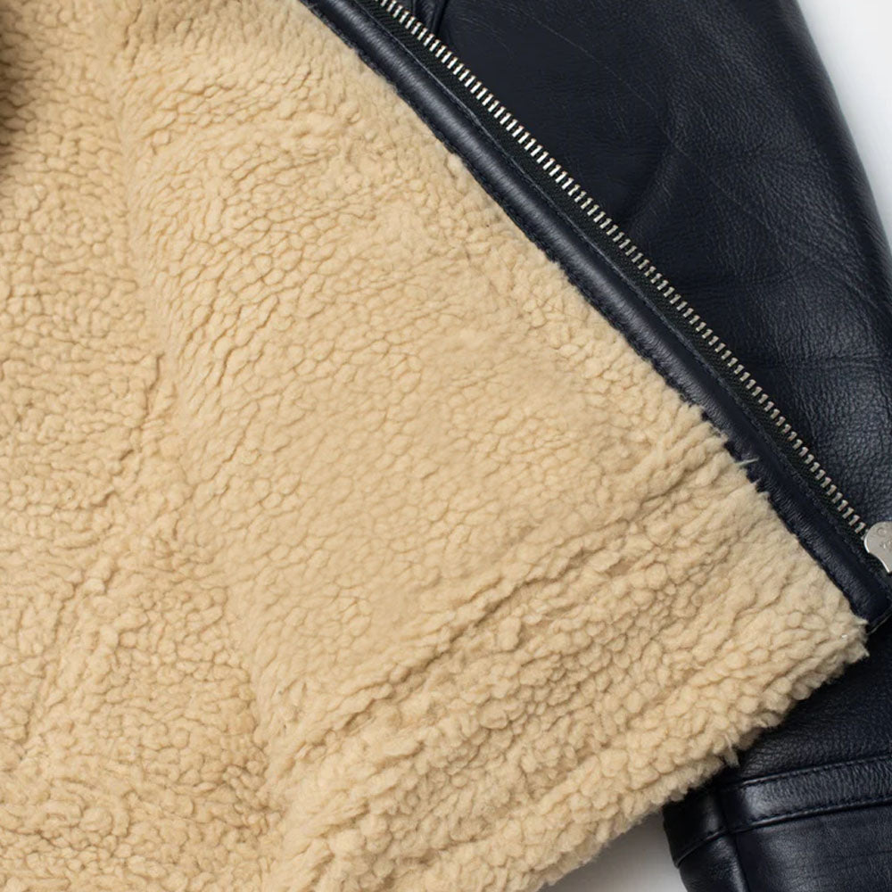 Macro texture view of dense soft beige shearling wool fleece interior lining next to front zipper placket